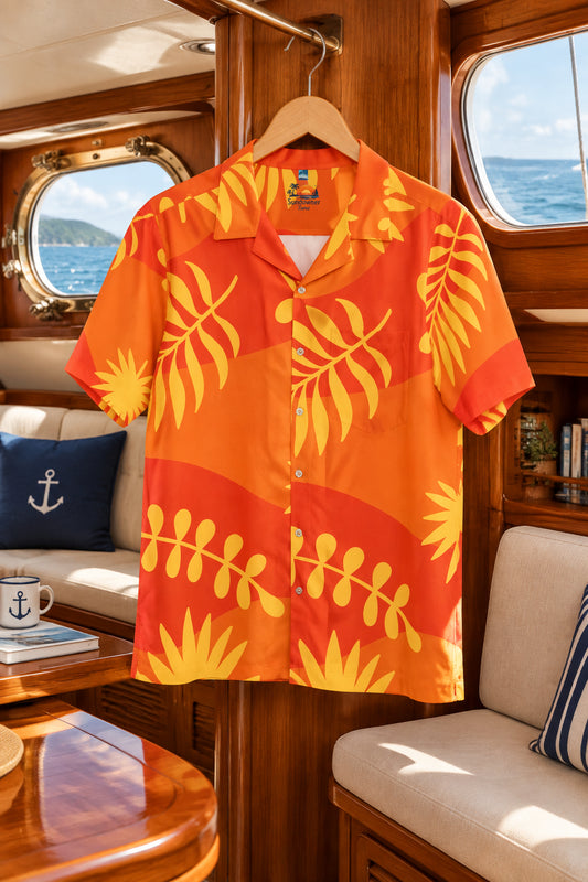A short-sleeve button-up camp shirt with a vibrant orange and red background featuring yellow tropical palm leaf patterns, laid flat against a white background.